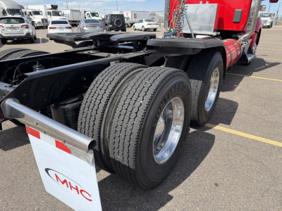 Kenworth T880 truck rear dual axle wheels and fifth wheel area with red cab and chrome fenders; visible tires and dual rear wheels.