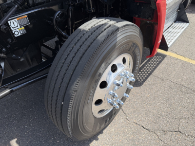 Wheel and tire close-up on Kenworth T880 truck with dual rear axle, polished chrome lug nuts, and tire sidewall text visible.