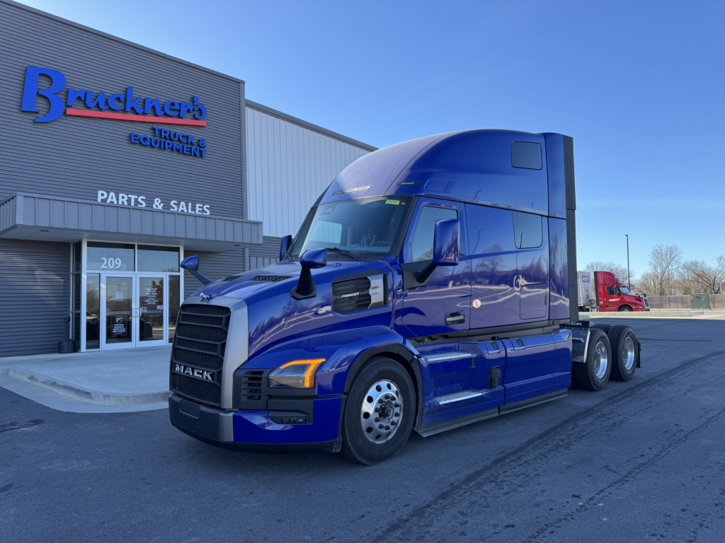2026 Mack PR64T76H truck in blue parked at dealership showing cab and front wheel area.