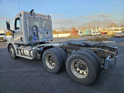 Truck chassis and cab of a Freightliner Cascadia126 tractor in view from rear/side showing dual rear axles and fuel tanks.