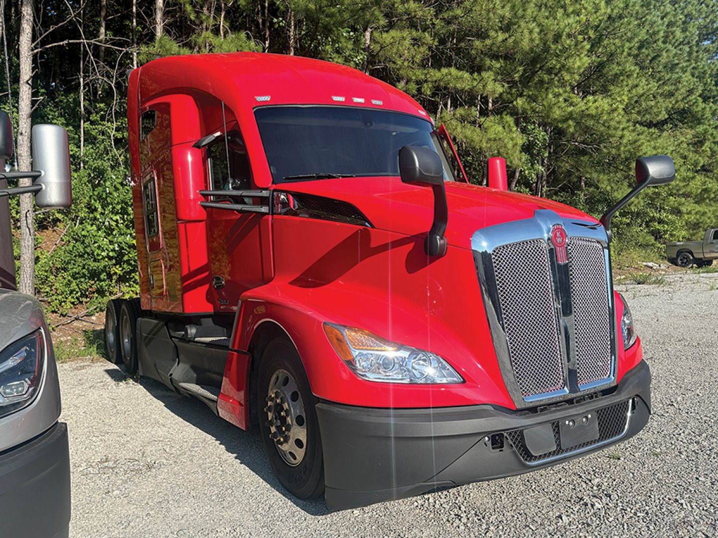 Kenworth T680 Next Gen tractor in red, front-left view with chrome grille and black bumper.