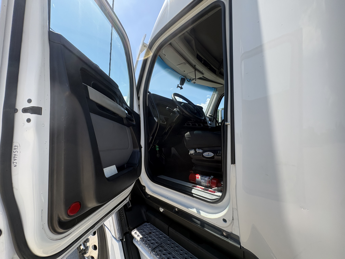 Truck cab entry with open door showing driver seat and dashboard of Kenworth T680