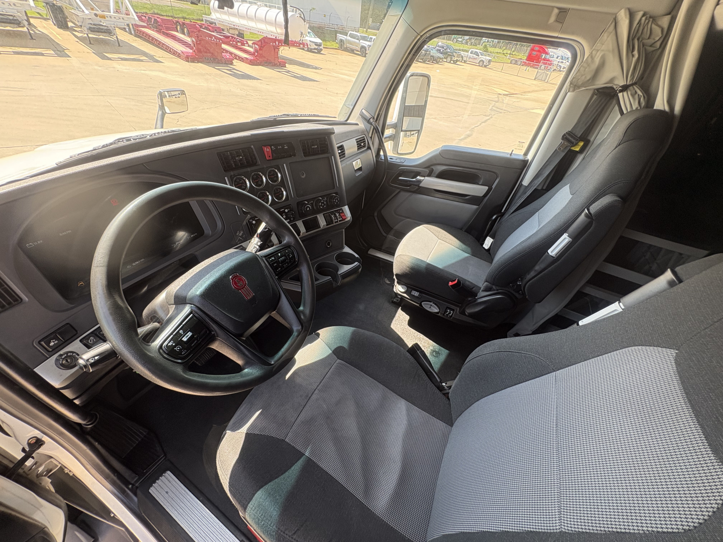 Kenworth T680 cab interior with steering wheel, dashboard, and front seats visible.