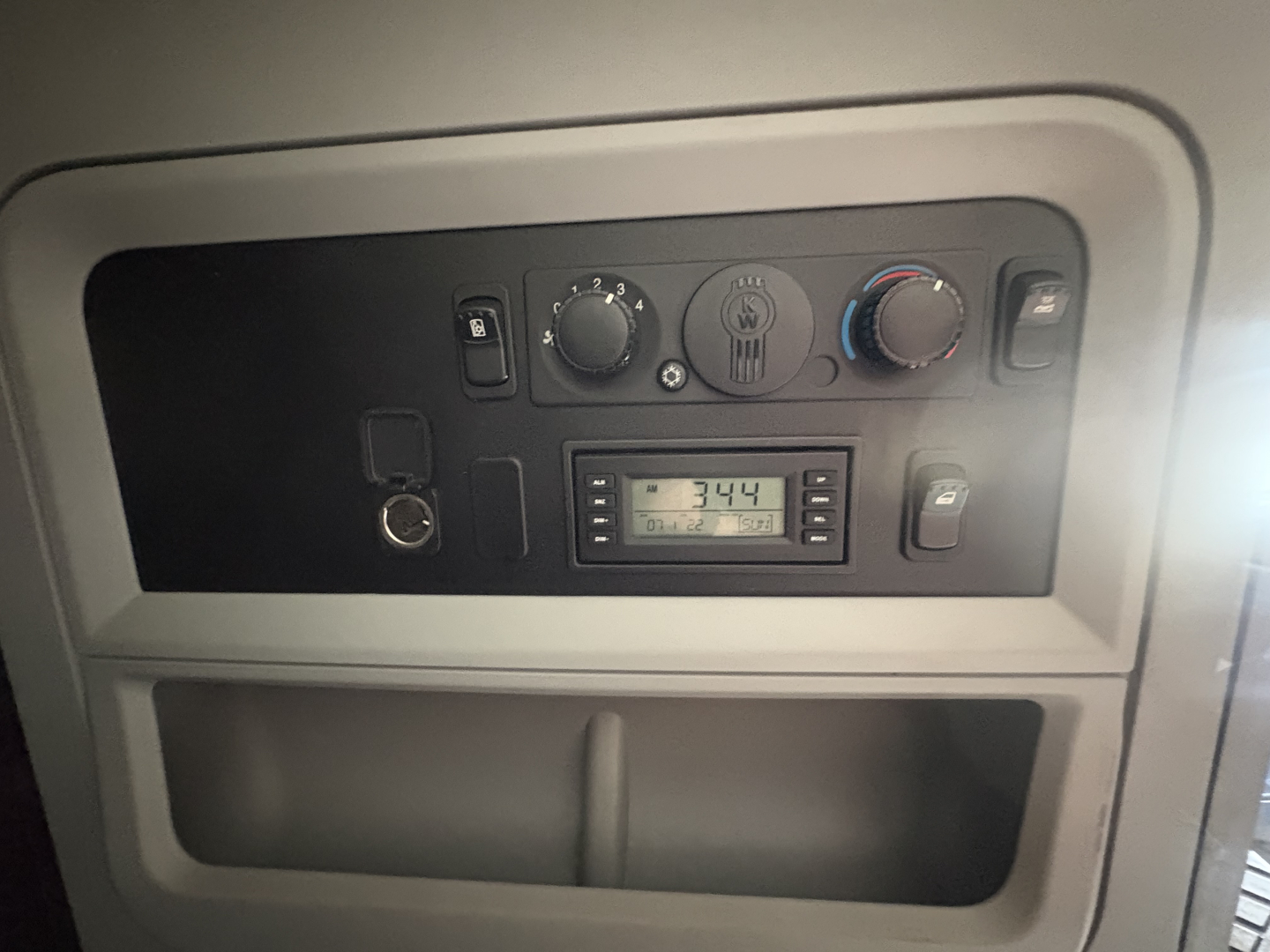 Kenworth T680 dashboard panel with climate controls, radio, and gauges visible in a sleeper cab area.