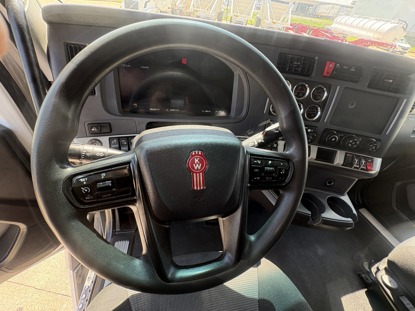 Kenworth T680 interior view showing steering wheel with KW logo, dashboard and control panels.