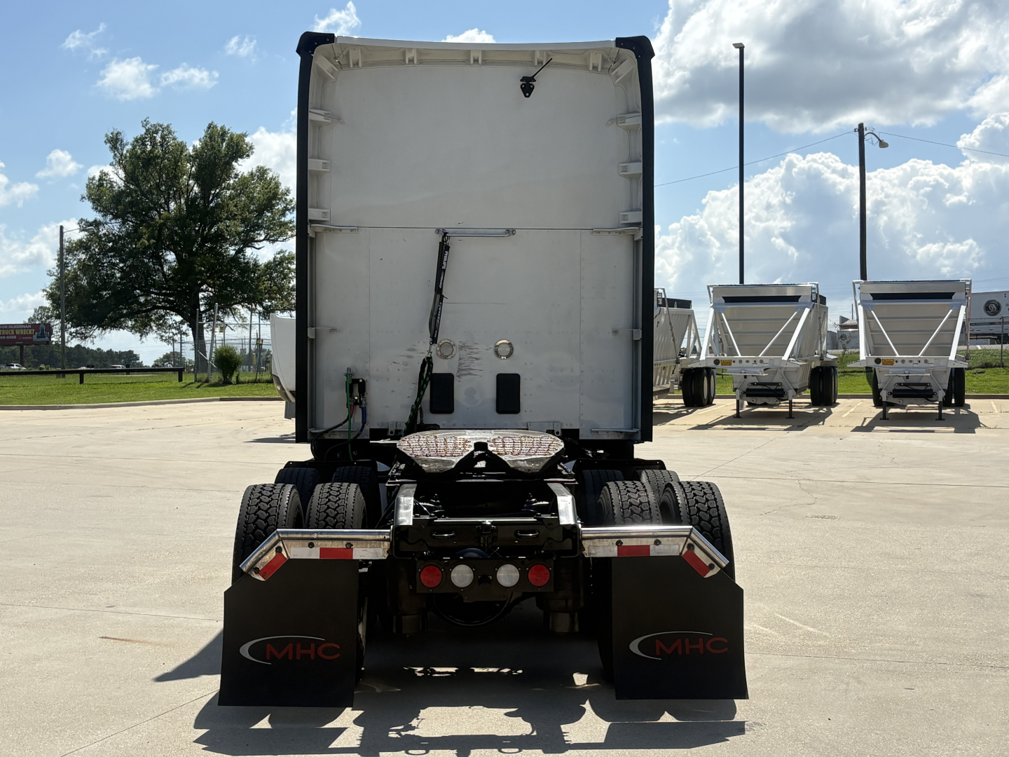 Kenworth T680 rear view showing tractor chassis and mud flaps with MHC logo.