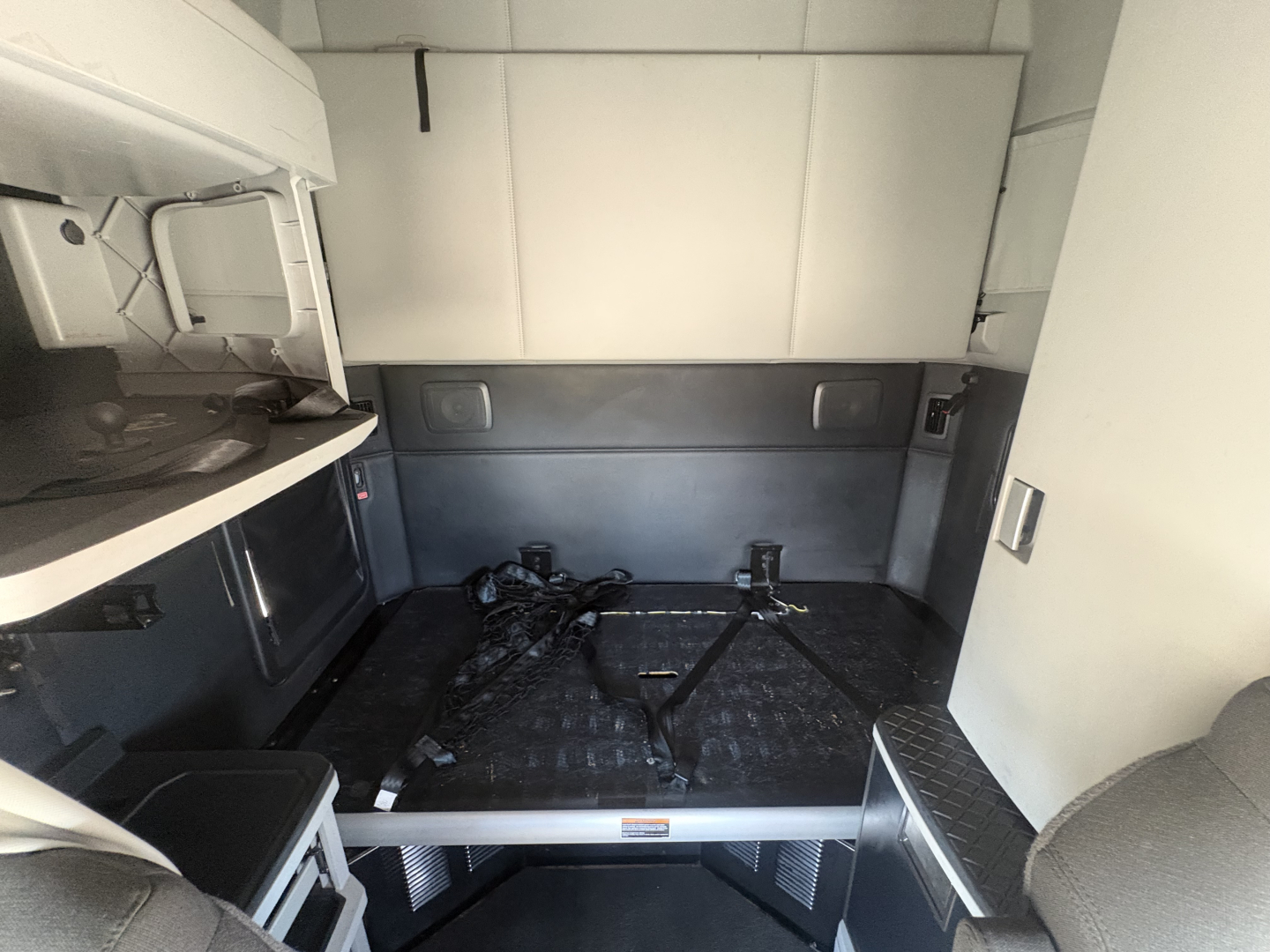 Kenworth T680 sleeper cab interior cargo area with bed platform and anchor straps visible.