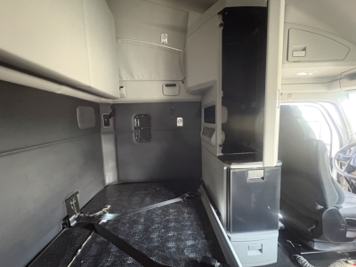 Kenworth T680 cab interior showing sleeper area and storage compartments with vertical cabinet and dashboard view.