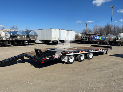 Trailer: lowboy/flatbed trailer with triple-axle setup and gooseneck, in a dealership lot with various trailers in background.