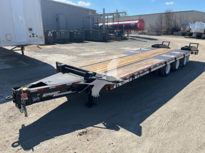 Trailer showing a long flatbed with wooden deck and dual-axle configuration, Eager Beaver logo on the hitch, and spare components on the tongue.