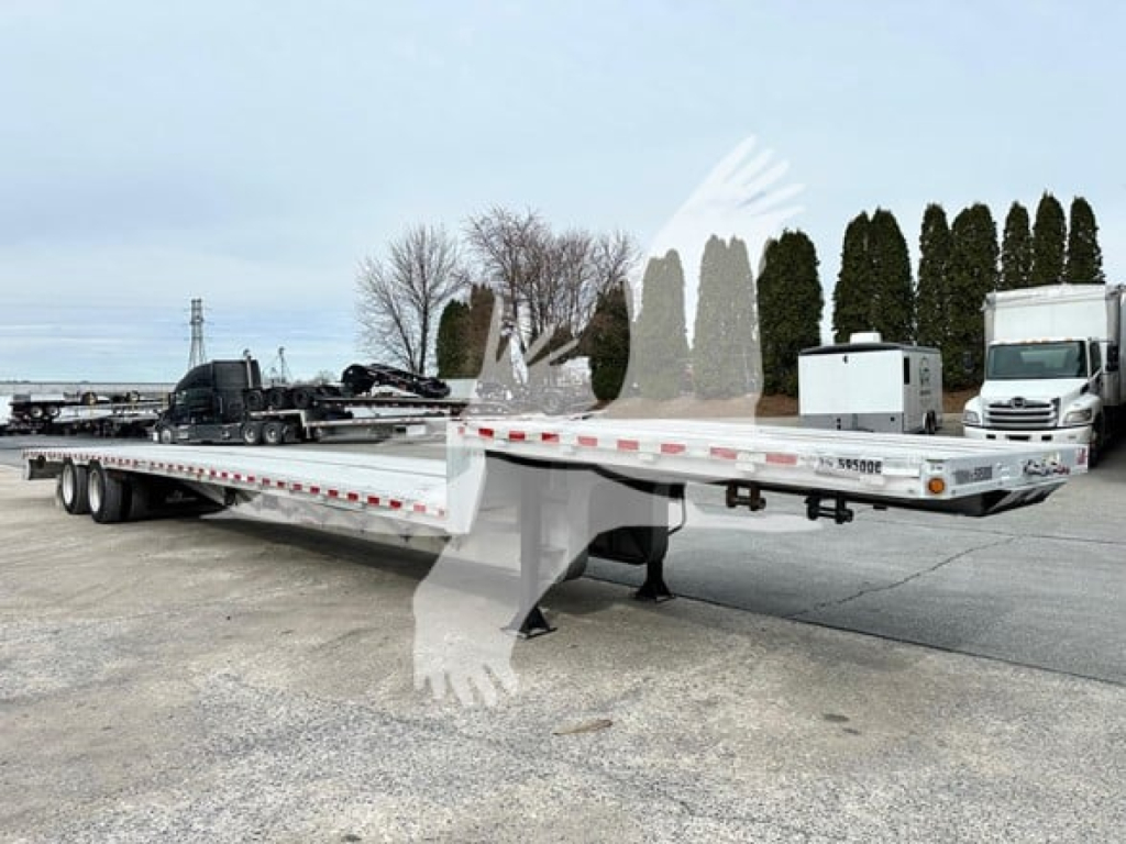 Trailer side view of a 2019 Reitnouer Dropmiser 53 lowboy trailer showing long aluminum deck with white and red reflective tape, dual rear axles, and a cab in background.