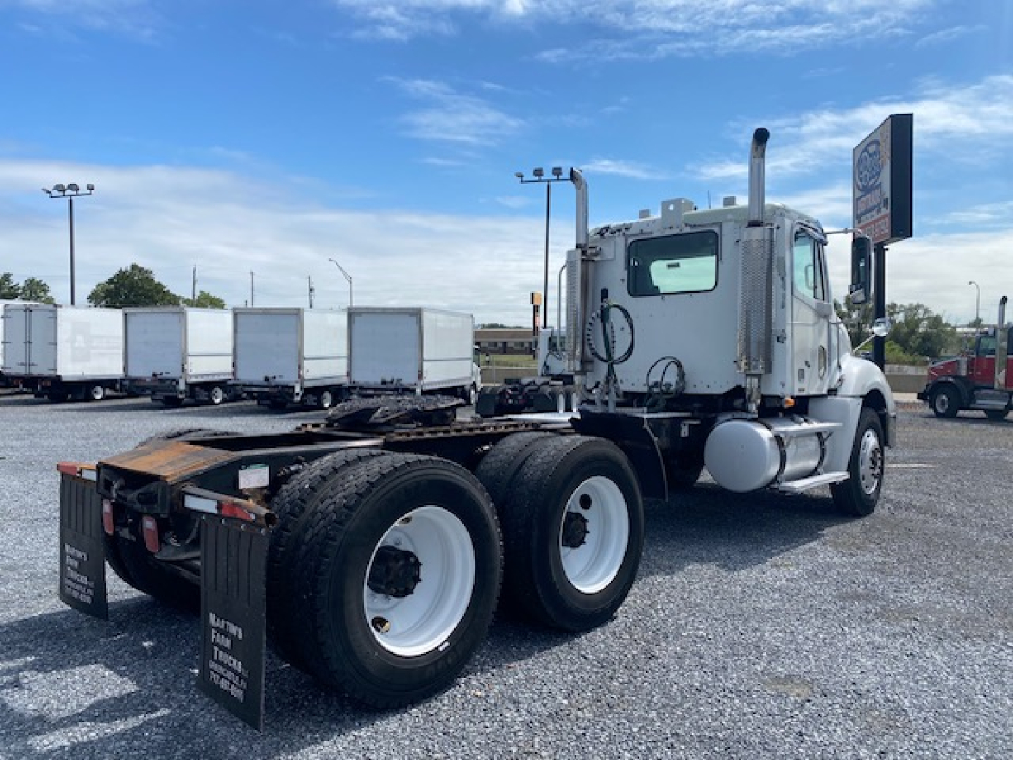Truck rear view of a Freightliner Columbia CL120ST conventional daycab with dual rear axles, white wheels, and fuel tanks on the side.