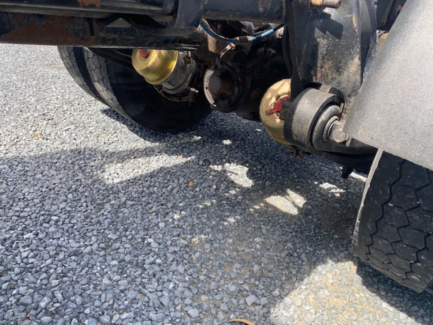 Freightliner Columbia CL120ST rear undercarriage showing drive components and suspension, with visible air lines and fuel/def fluid reservoirs.