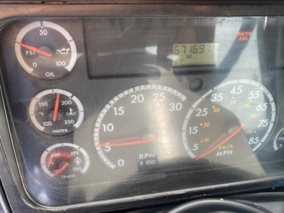 Dashboard view of a Freightliner Columbia CL120ST showing gauges: PSI oil pressure, water temp, transmission, RPM x100, speedometer, and an odometer display reading 671,695 miles.