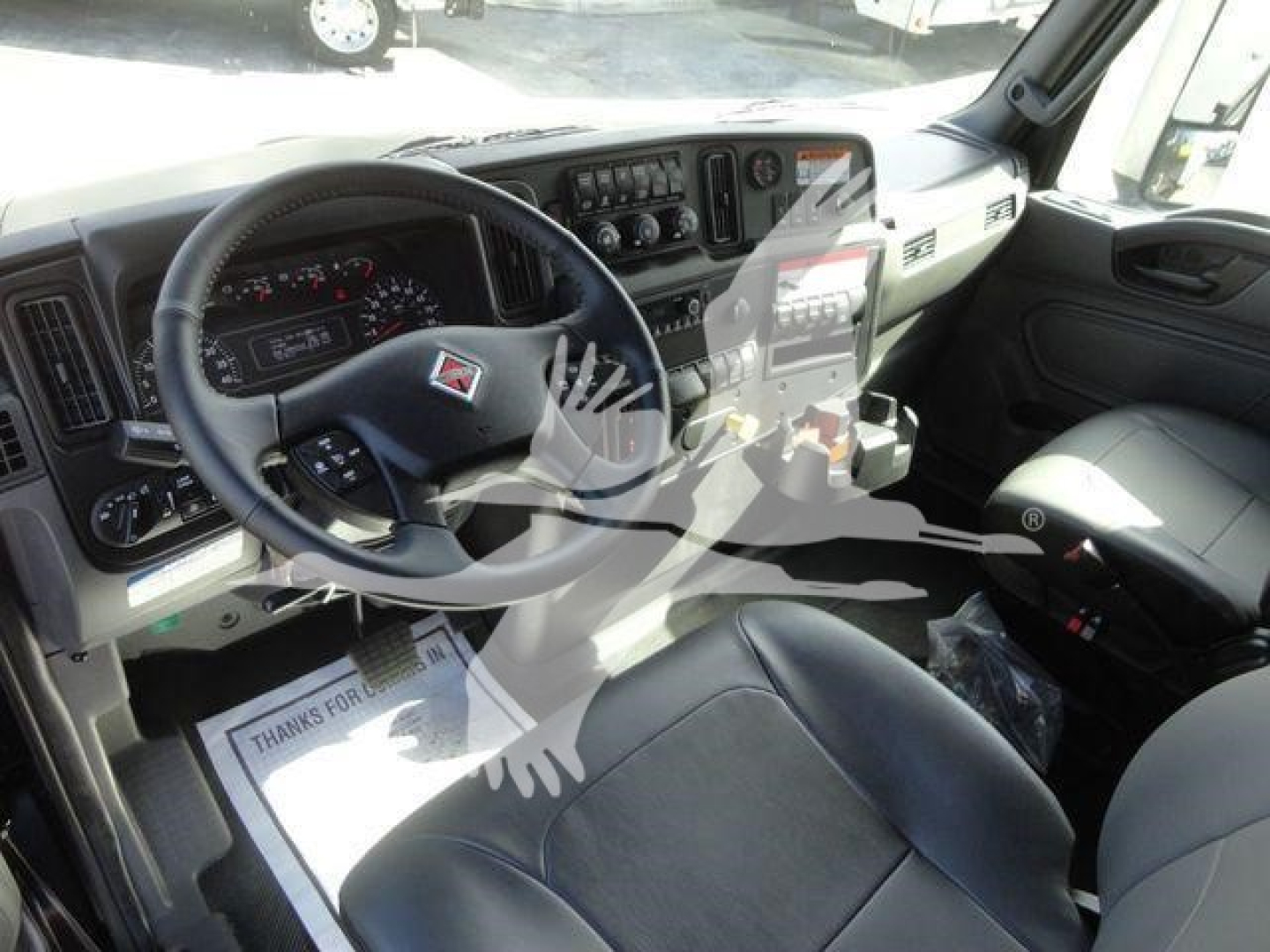 Truck cabin interior showing steering wheel, dashboard, and driver seat of a 2027 International MV truck.