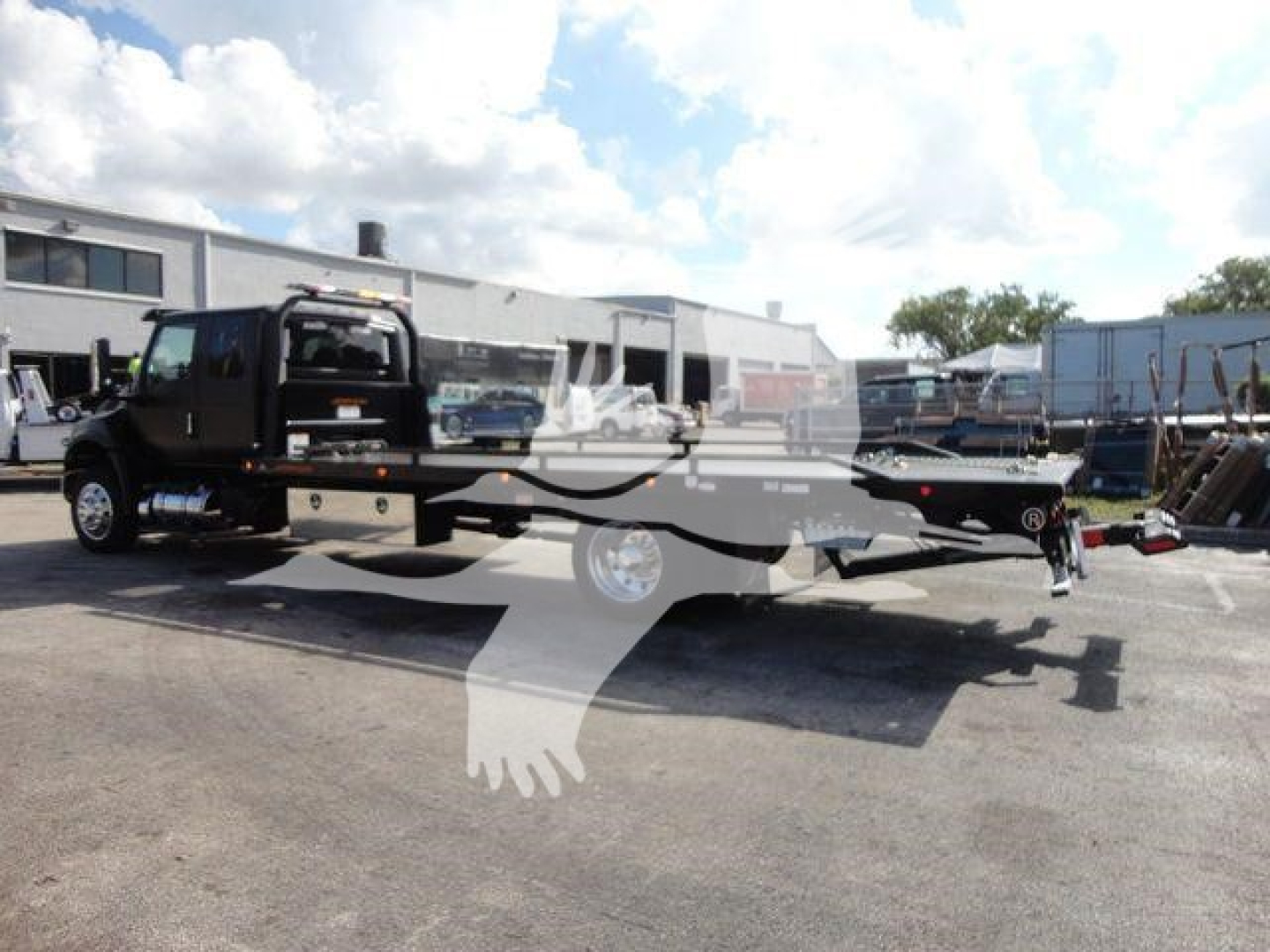 Flatbed rollback tow truck in a dealership lot with stock number J47176 and new, category rollback. The image shows a black tow truck with a long flatbed and equipment in background.