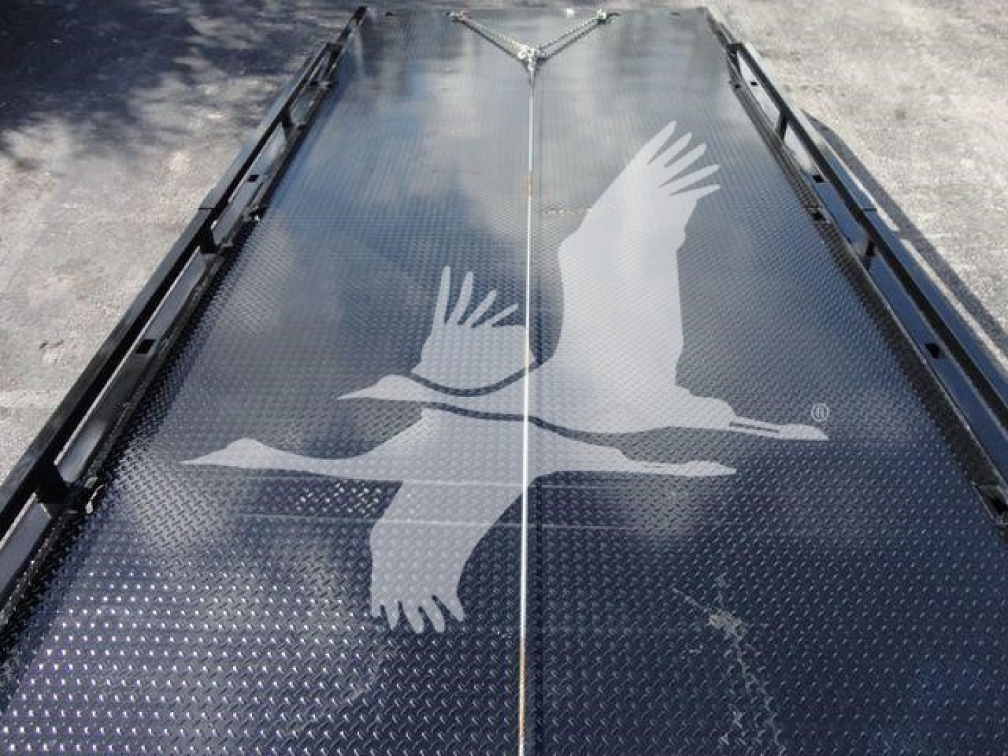 Flatbed equipment with diamond plate surface and central hinge, showing a starling logo on the deck.