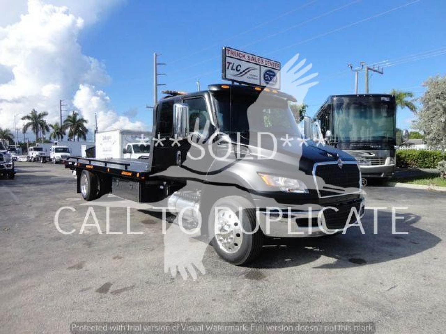 Flatbed tow truck in service bay showing cab and long hauler bed with 'SOLD' watermark
