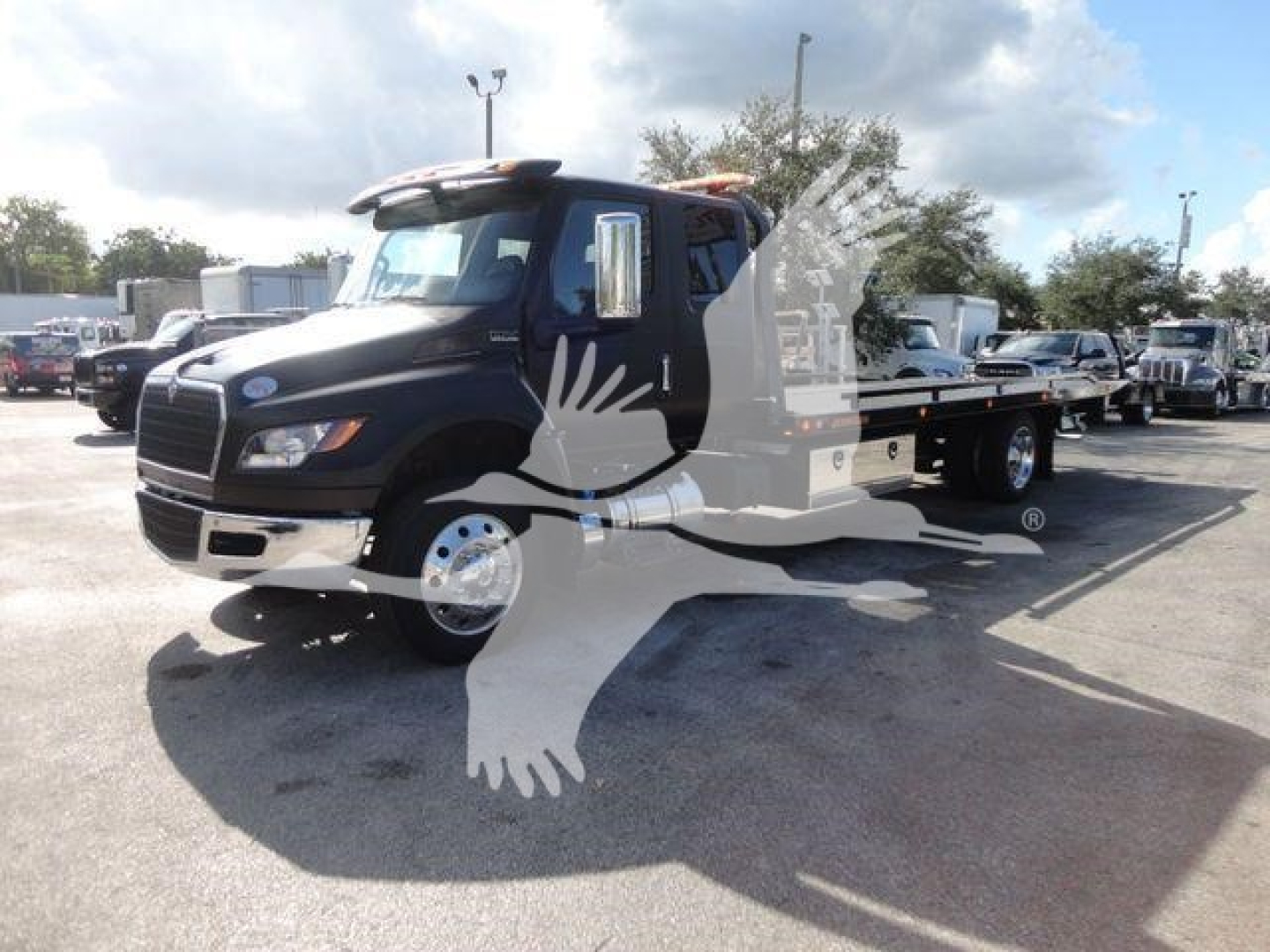 Truck chassis in a lot showing 2027 International MV rollback body with flatbed and dual rear wheels.
