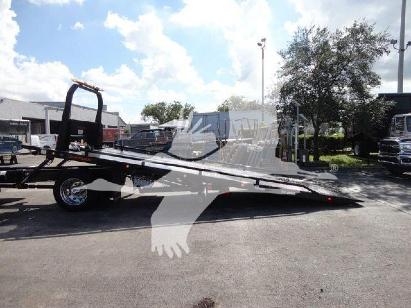 International MV rollback truck with flatbed tilt bed and wheel, side view showing loading ramp and hitch.