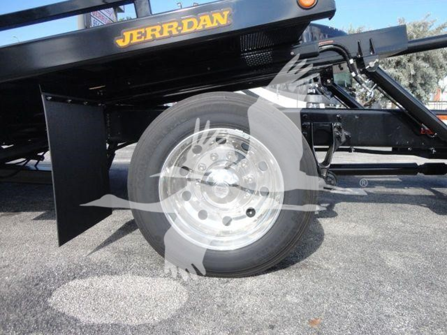 Wheel and lower frame of a 2027 International MV rollback truck showing alloy wheel and tire with black undercarriage components.