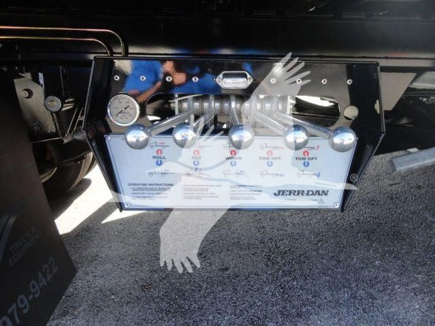 Trailer brake control panel with multiple toggles and a Jerr-Dan branding; plumbing lines and metal framework visible, on a rollback truck chassis.