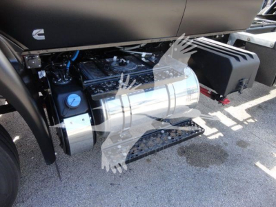 Truck engine bay showing cylindrical fuel tank and metallic components on left, side steps and black plastic fairing on right.
