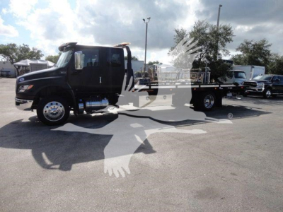 International MV rollback truck in view showing cab and chassis with flatbed.