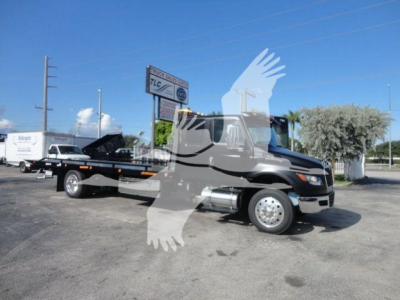 Truck body with a rollback tow truck in a dealership lot, cab-front view, International MV model, black and chrome exterior, stock number J47176.