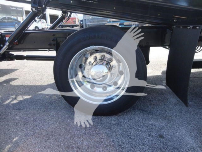 Truck wheel and suspension view showing a shiny steel wheel and black undercarriage components.