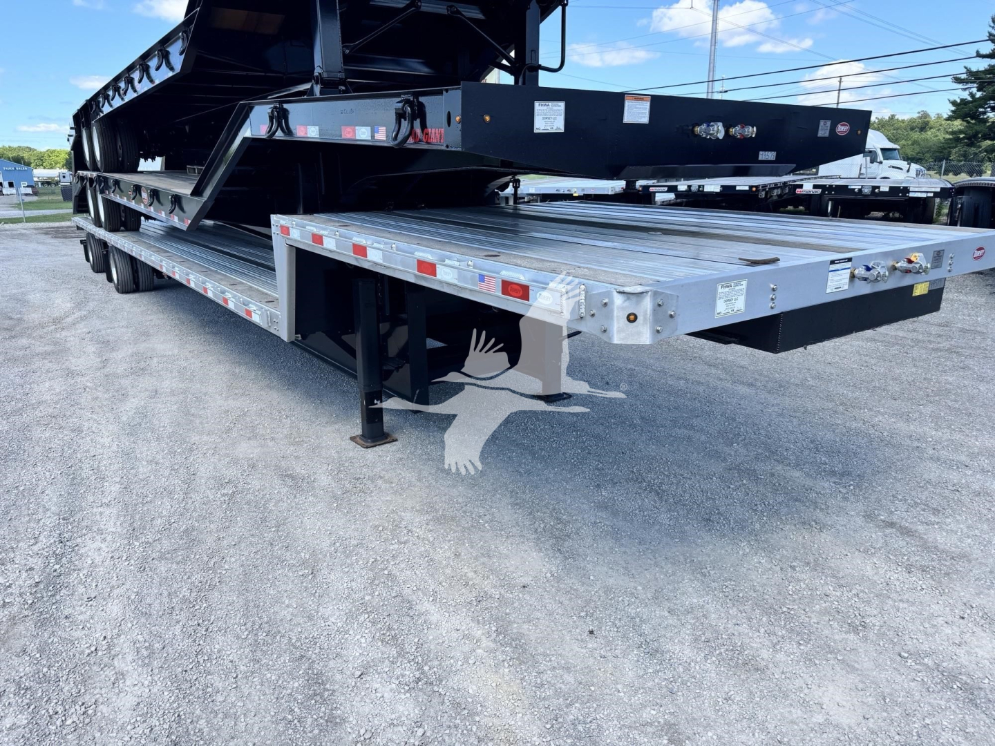 Low-angle view of a Dorsey Combo Drop trailer showing a long silver deck with black support structures and landing gear.