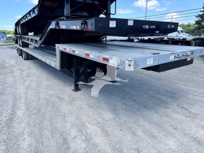 Low-angle view of a Dorsey Combo Drop trailer showing a long silver deck with black support structures and landing gear.