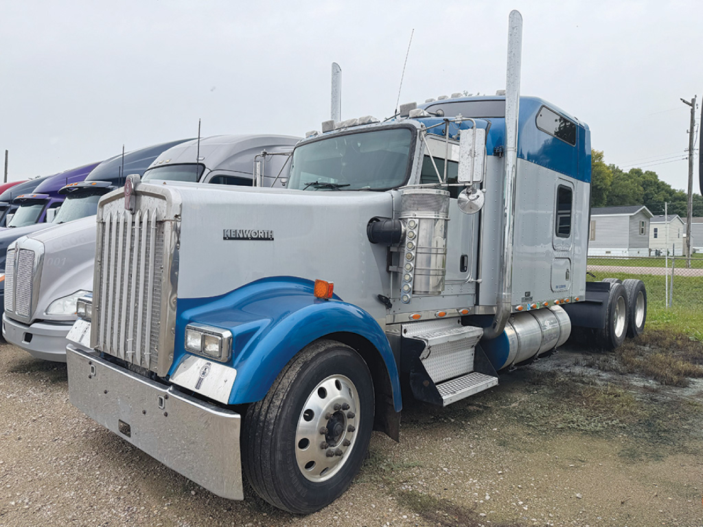 Kenworth W900L AeroCab truck in blue and silver, front left angle, with chrome grille, large bumper, dual side exhausts, and sleeper cab.
