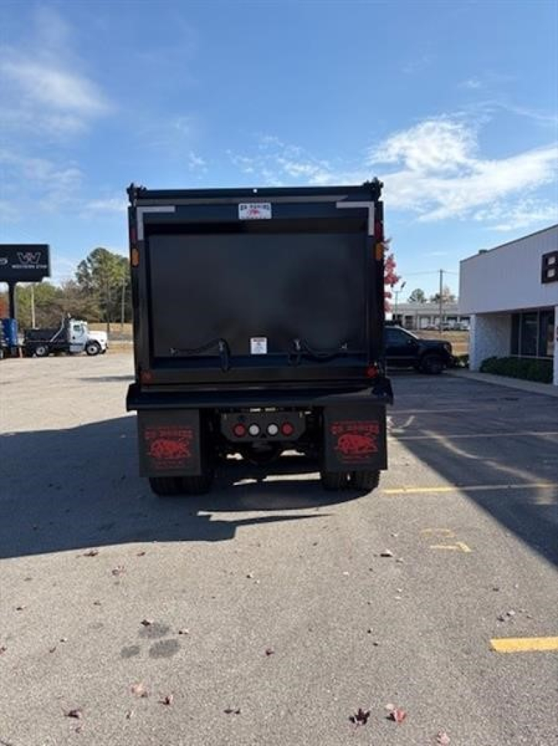 Dump truck bed back view showing tailgate, undercarriage, and rear lights of a new Western Star 49X in a dealership lot.