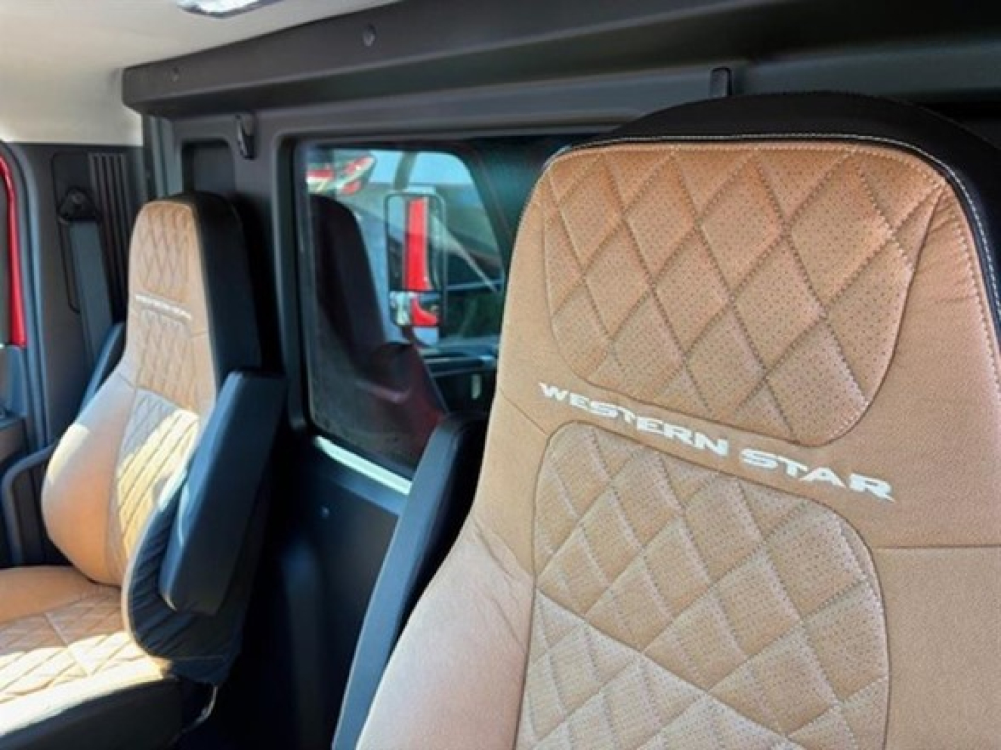Western Star 49X interior seating with diamond-stitched tan leather seats and 'WESTERN STAR' logo on the seat back, front cab view.
