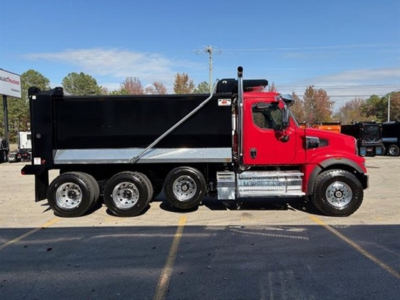 Dump truck side view showing red cab and six-wheel dump bed with hydraulic tarp system and chrome steps.