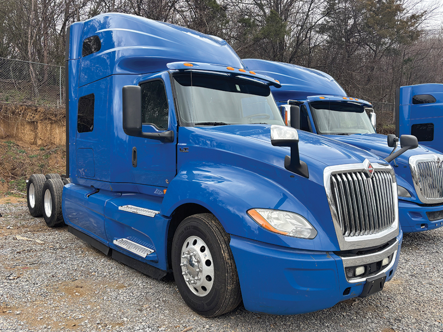 Blue International LT Series truck cab in profile view with sleeper, front grille, and dual rear axles visible.