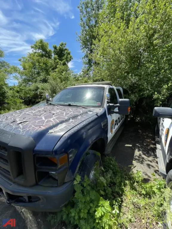 Ford F-250 Super Duty police vehicle with cap, front-left view, showing partial door decal and cruiser markings.