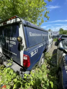 Ford F-250 Super Duty emergency vehicle with cap, police unit markings, rear-side view showing Emergency Services Unit text and 9-1-1 emergency decals.