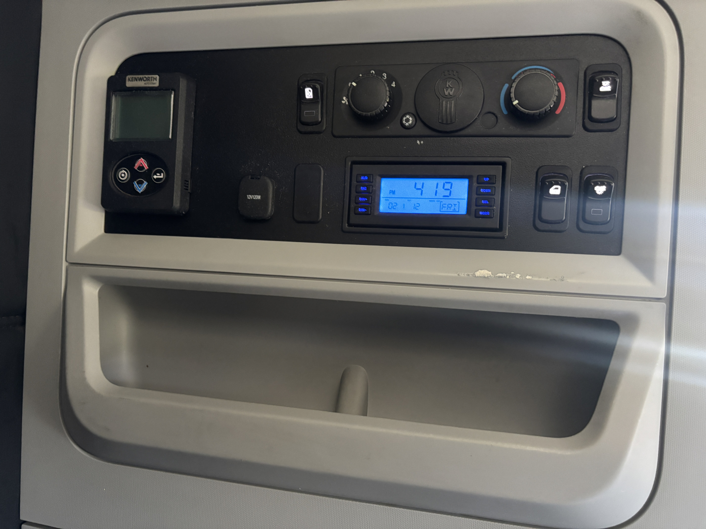 Kenworth T680 dash controls and radio display showing climate knobs and digital screen.