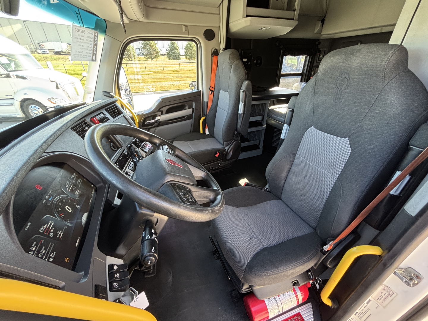 Kenworth T680 truck interior showing driver seat and dashboard with steering wheel and controls.
