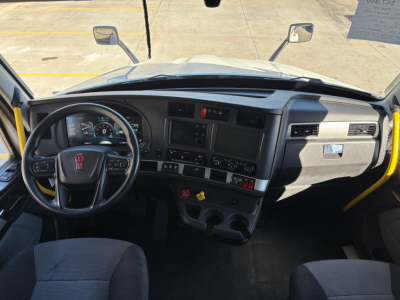 Kenworth T680 truck cabin interior view from driver seat with dashboard gauges, steering wheel, and center console; windshields and mirrors visible.