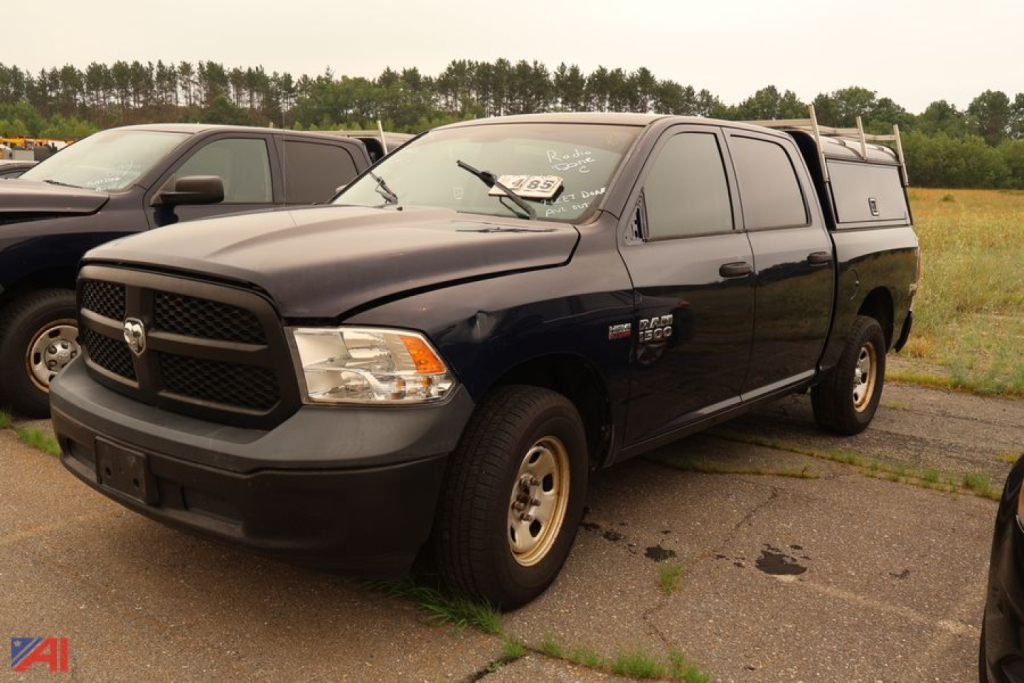 Ram 1500 pickup truck with cap, dark blue color, front three-quarter view in a parking lot.