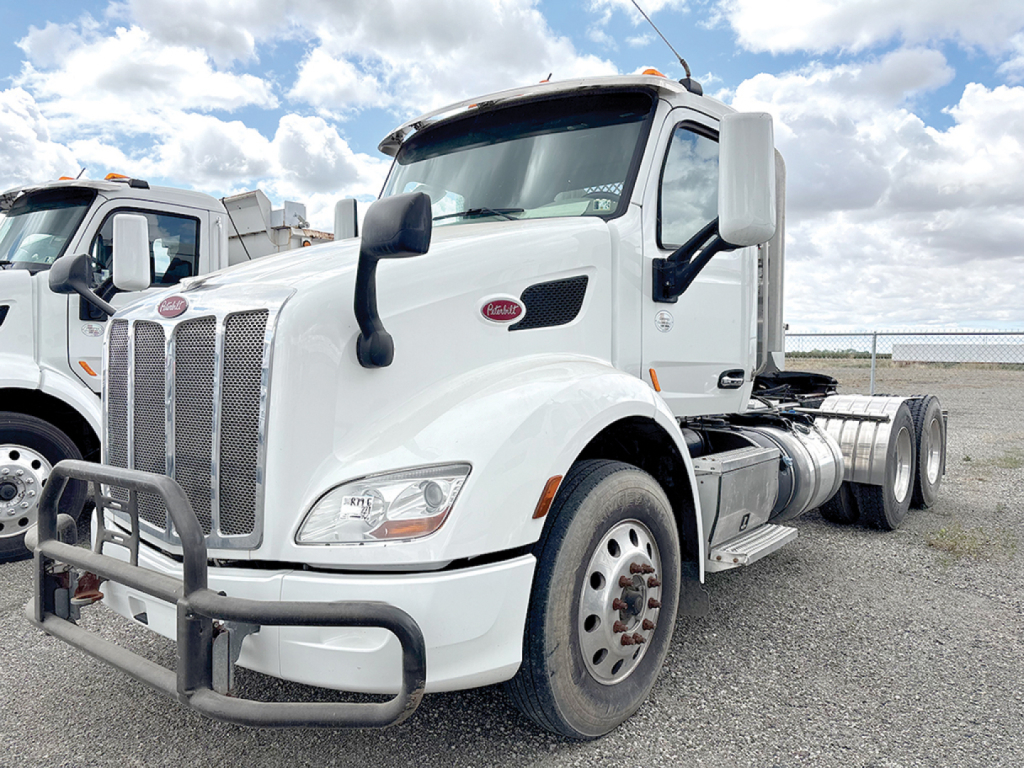 Peterbilt 579 conventional daycab truck in white from front-left view showing bumper guard and side fuel tanks.