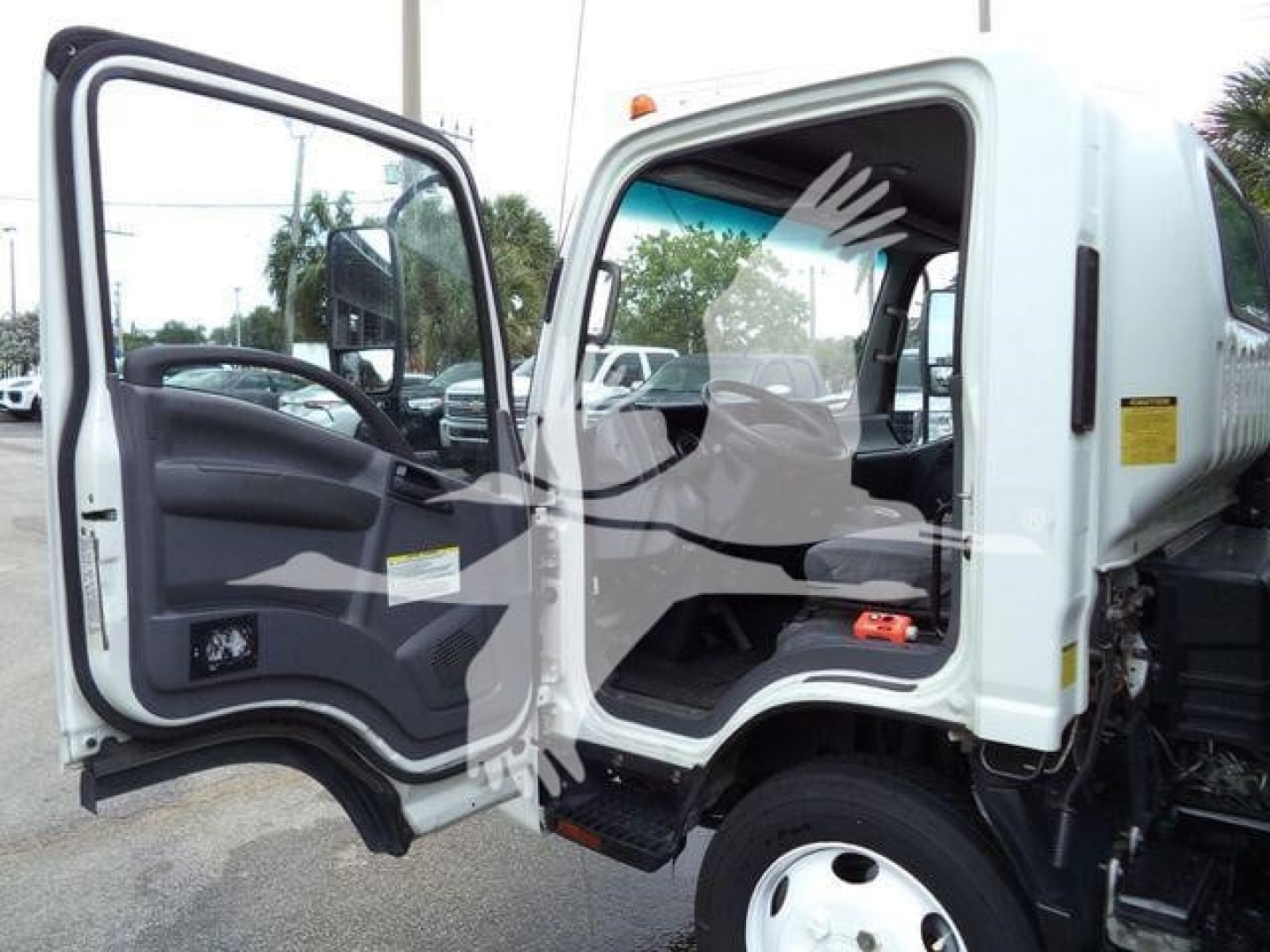 Isuzu NPR-XD cab interior and open door showing step and seat area, front wheel, and dashboard area.