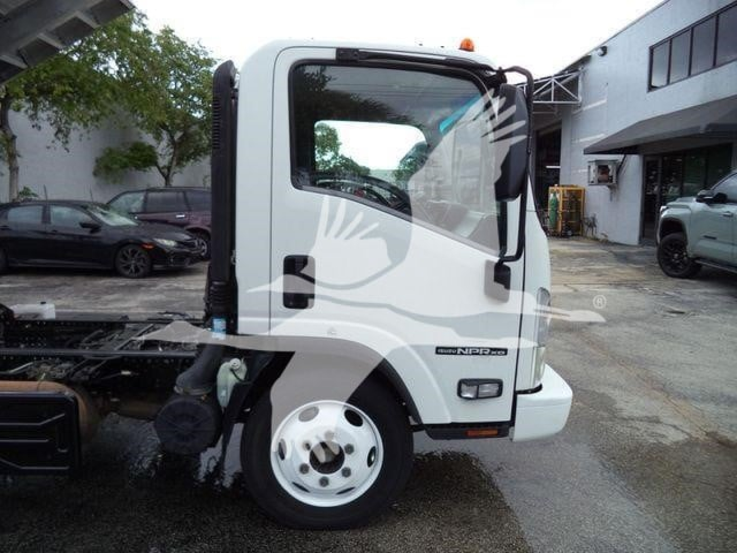Isuzu NPR XD truck cab side view showing front wheel and door with Isuzu badge and NRRNP model label.