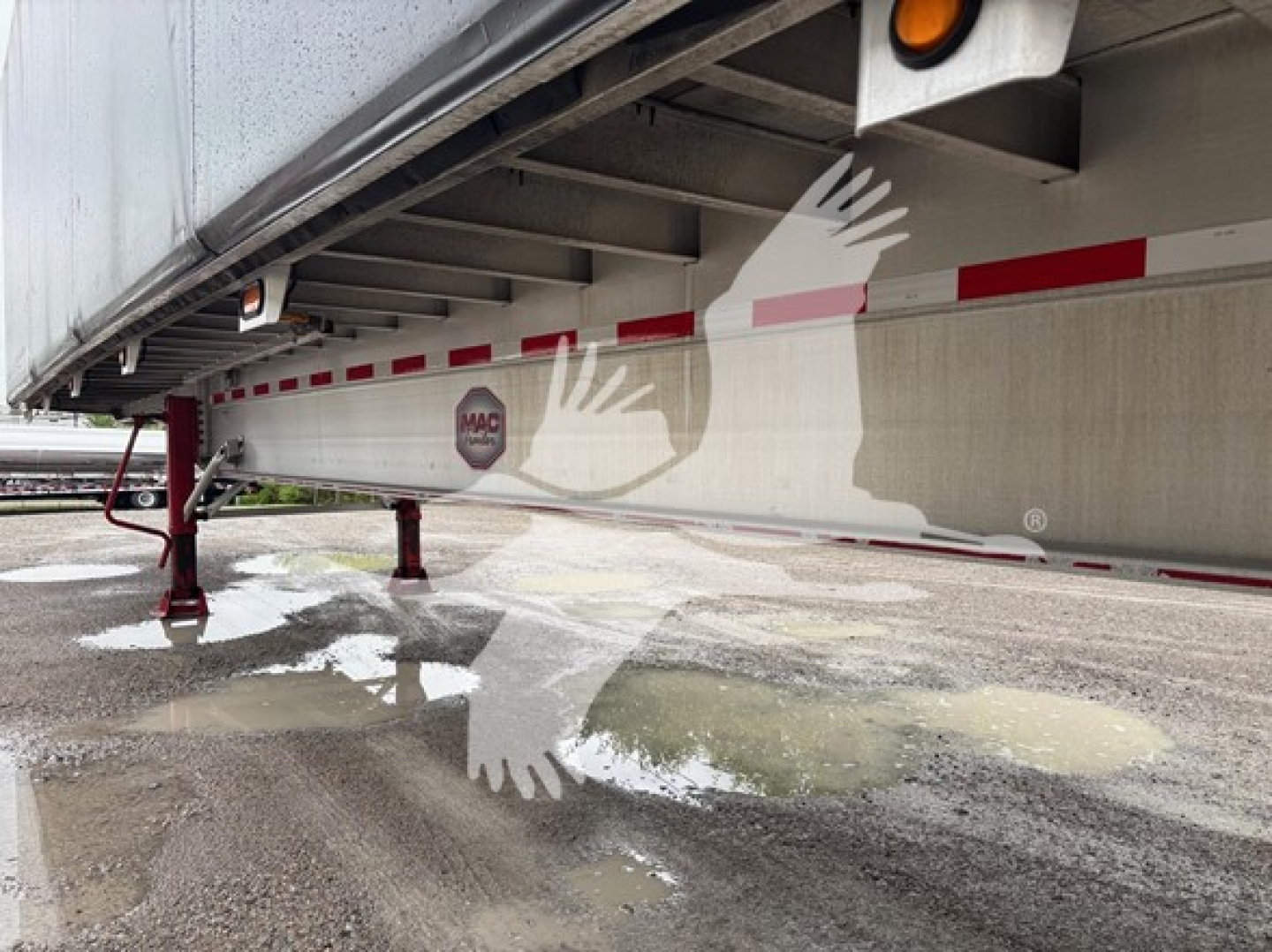 Mac Road Warrior trailer undercarriage showing support legs and reflection on wet ground