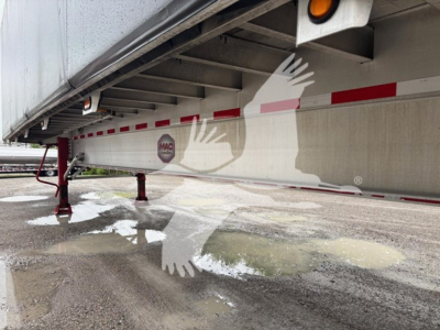Mac Road Warrior trailer undercarriage showing support legs and reflection on wet ground