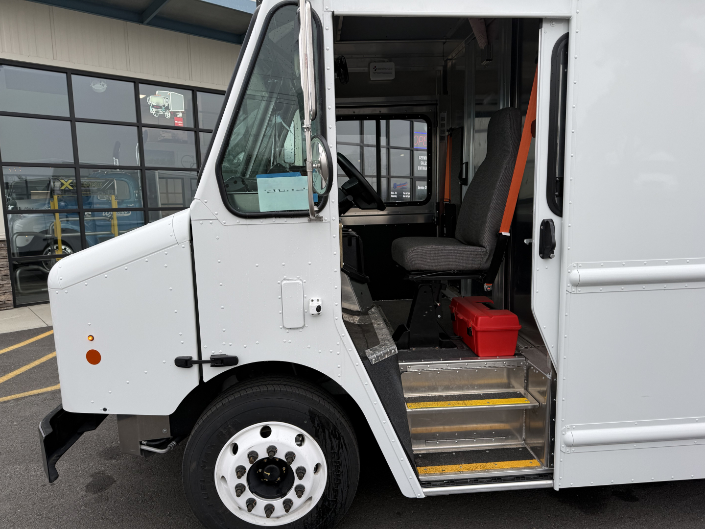 Harbinger S655 step van cockpit visible with front door open showing driver seat and interior steps with yellow edge markings.