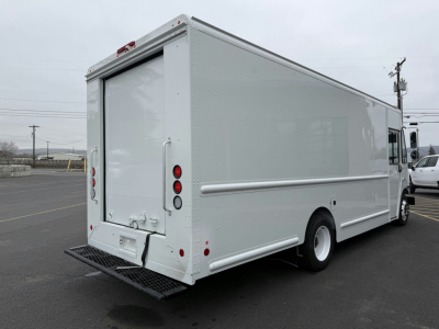 Harbinger S655 step van rear and side view showing raised rear doors, white exterior, cargo area, taillights, plinth steps, and wheel hub.